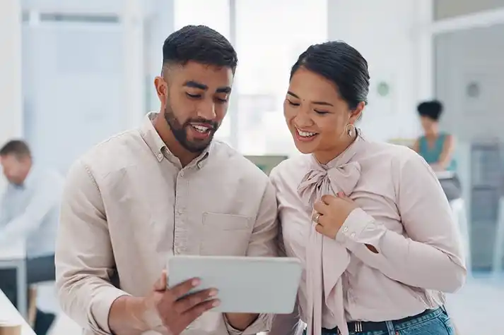  Hispanic male and Asian female coworkers looking at a tablet