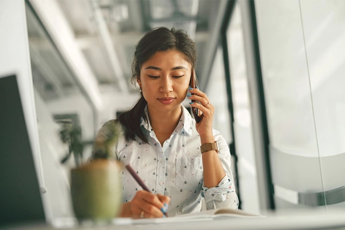 Female employee sits at a desk using her cellphone