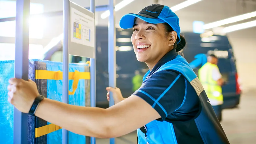 Hispanic female smiling while steering a cart in a warehouse.