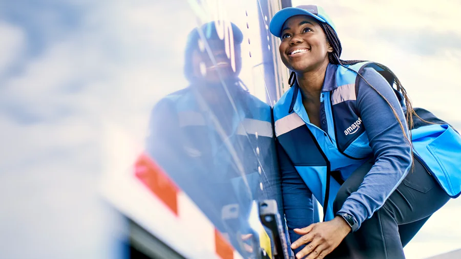 Black female smiling while opening the back door of a delivery truck.