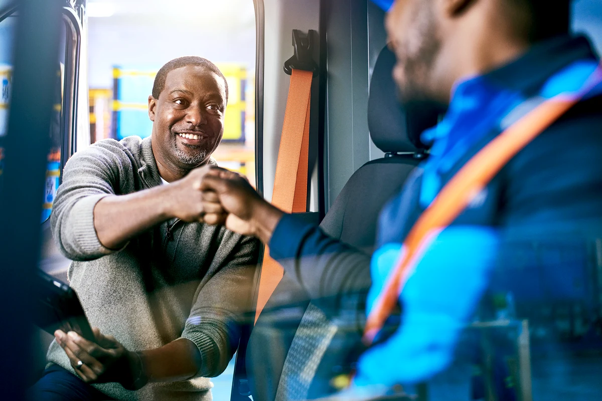 Black male manager fist-bumping a Black male delivery driver.