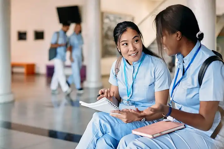 An Honor Health employee sits on a bench inside a hospital next to a female employee